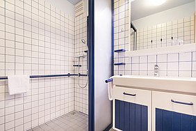 Blick in ein kontrastreich ausgestattetes Badezimmer mit barrierefreier Dusche.