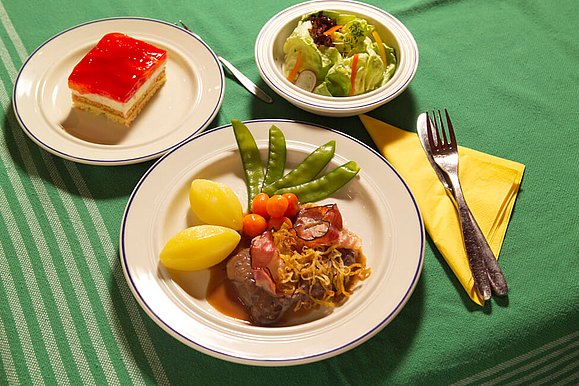 Dreigängiges Menü mit Salat, Kuchen, Fleisch und Gemüse.